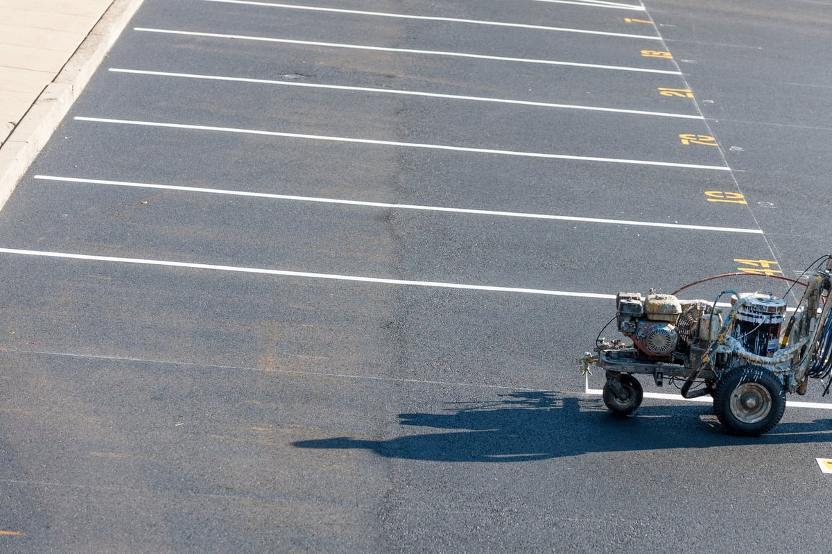 Freshly striped commercial parking lot lines being painted